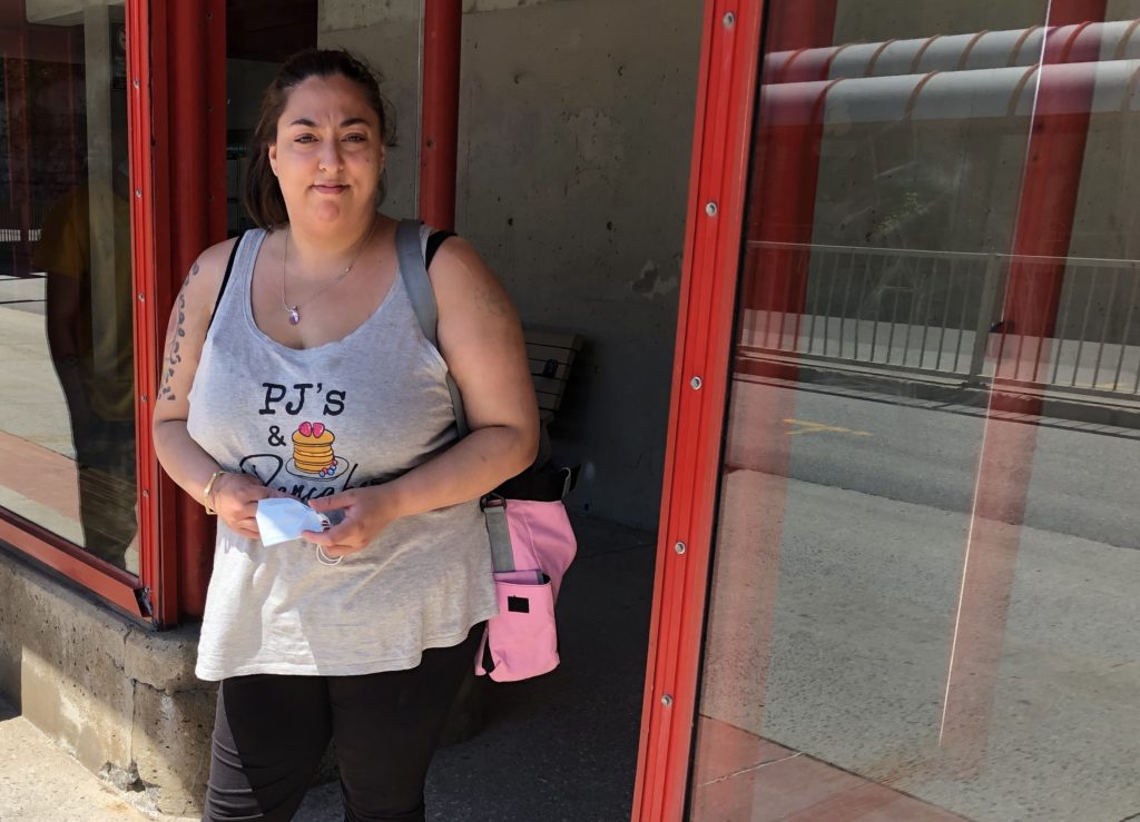 Photo of Crystal Nadiajiwn holding a face mask in her hands while she waits for the bus