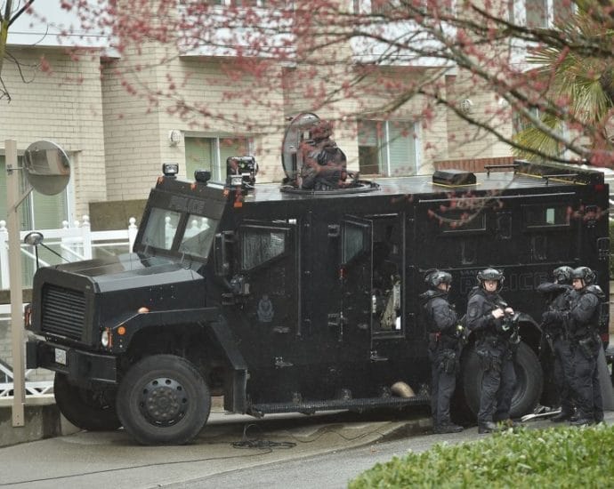 A group of Vancouver Police Department officers in tactical gear standing beside a police van