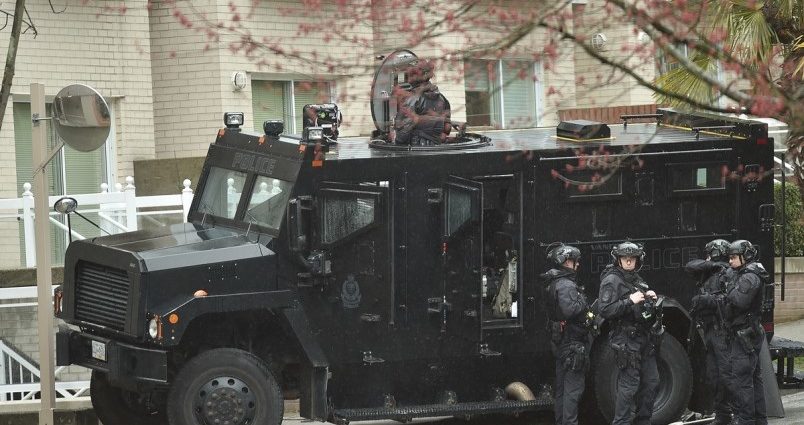A group of Vancouver Police Department officers in tactical gear standing beside a police van