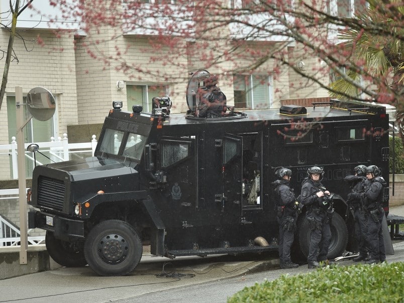 A group of Vancouver Police Department officers in tactical gear standing beside a police van