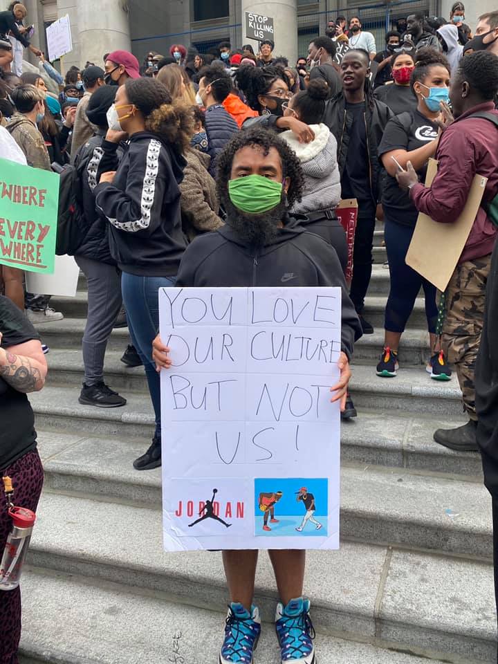 Youeal Abera stands on the front steps of the Vancouver Art Gallery at Sunday’s protest with a sign that reads “You love our culture but not us!”