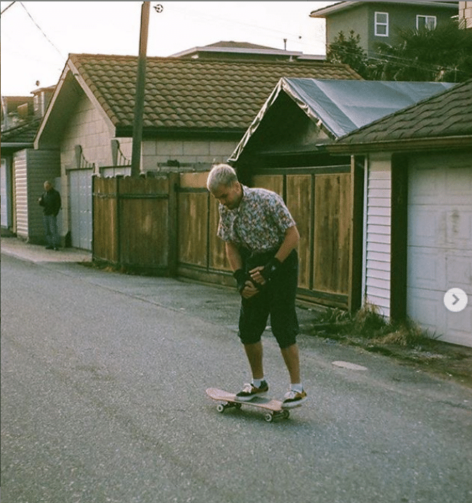 A photo of Jonah Bayley skateboarding in front of a row of houses