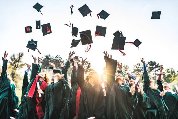 Graduates toss their caps in a stock image.