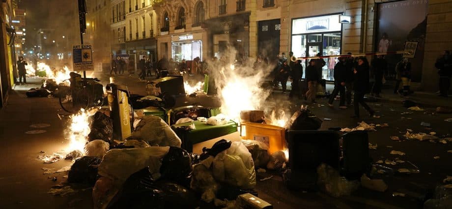 Garbage is set on fire by protesters after a demonstration near Concorde square, in Paris, Thursday, March 16, 2023. French President Emmanuel Macron has shunned parliament and imposed a highly unpopular change to the nation's pension system, raising the retirement age from 62 to 64. (AP Photo/Lewis Joly)